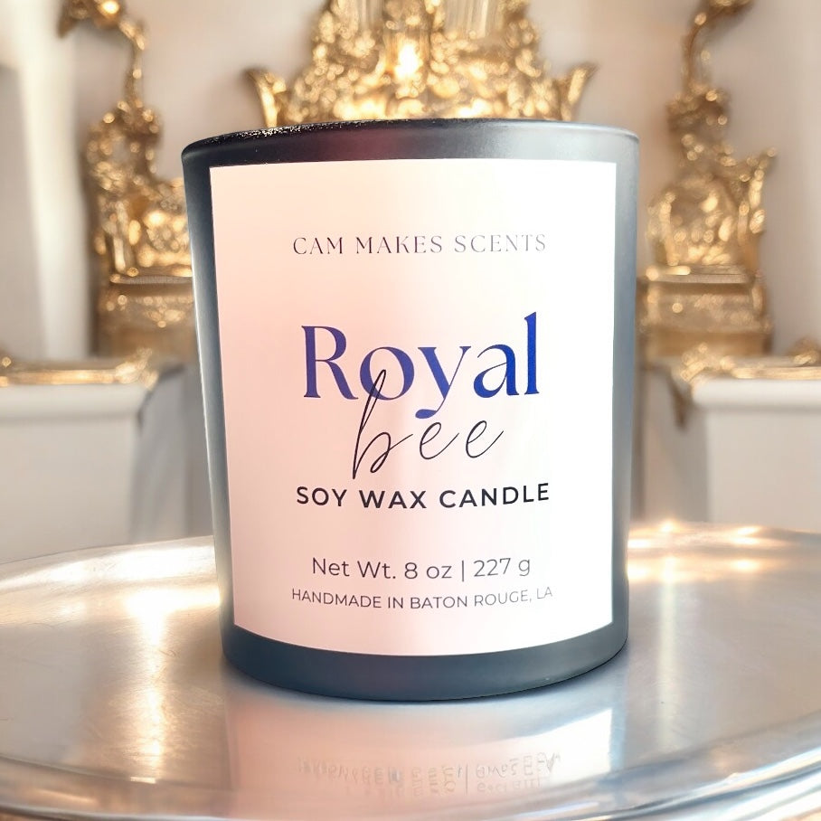 8 oz soy wax candle in a black jar labeled Royal bee surrounded by elegant gold structures. 